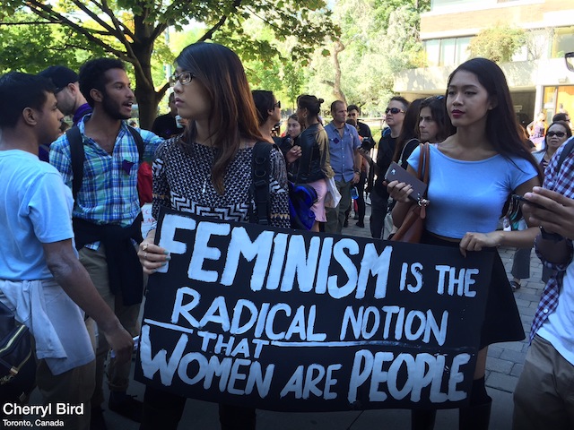 Students carry a sign that reads "FEMINISM is the radical notion that WOMEN are PEOPLE." Photo by Cherryl Bird